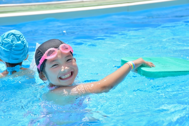 ピンクの水泳用ゴーグルをつけてプールに入る女の子