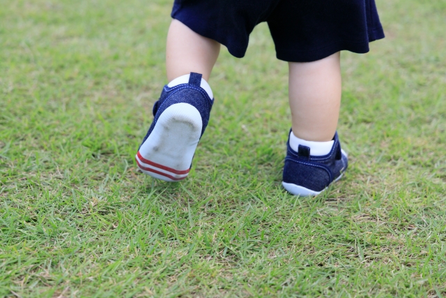 芝生の上を靴を履いて歩く子供